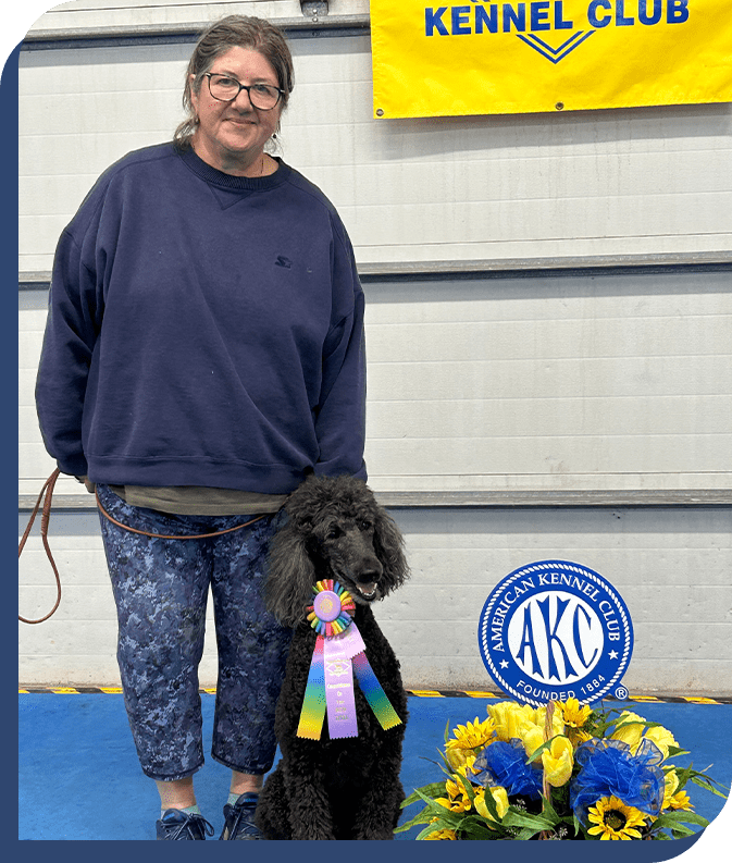 A woman standing next to a black dog.